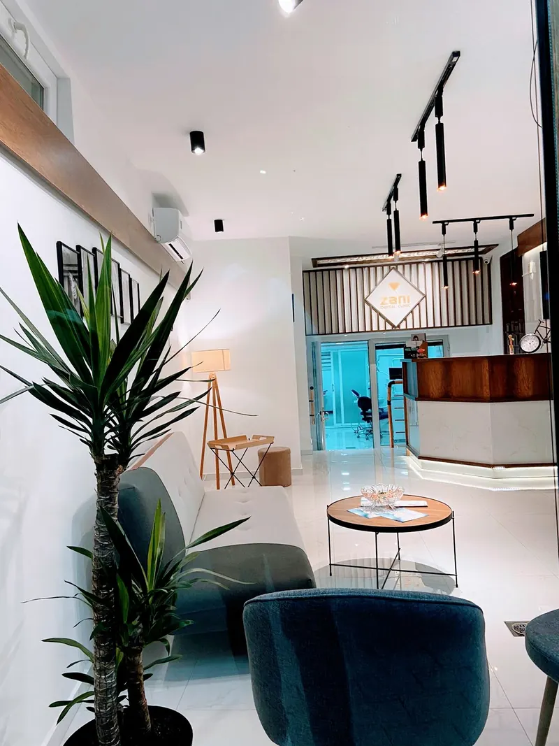 The waiting lounge with a plant, sofa and the reception desk behind